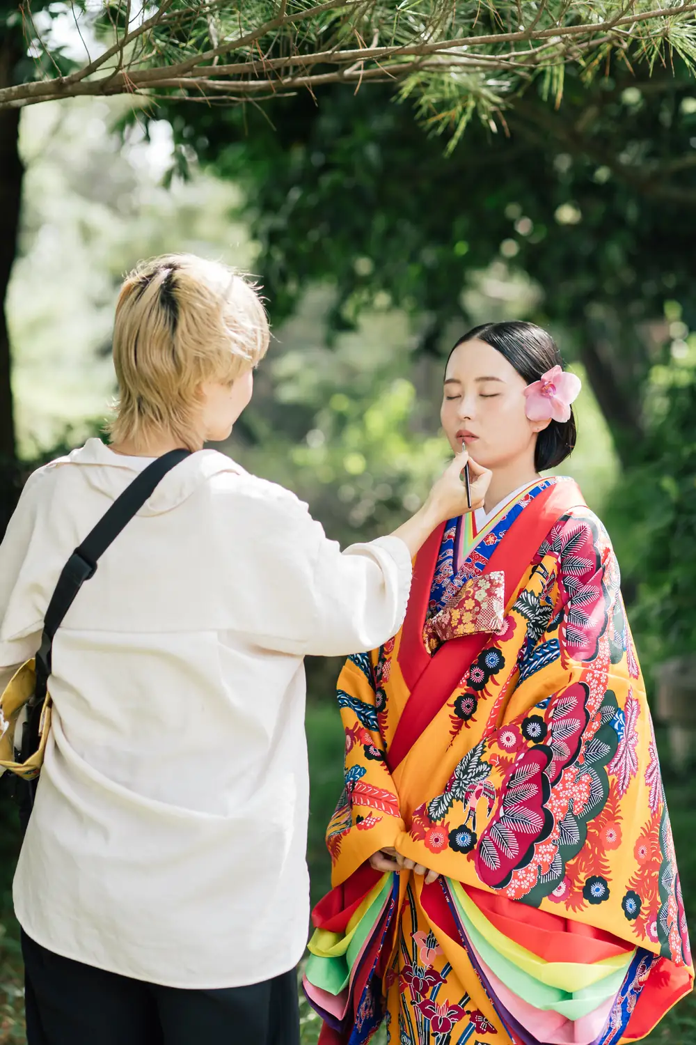 琉装の女性にヘアメイクを施すスタッフ