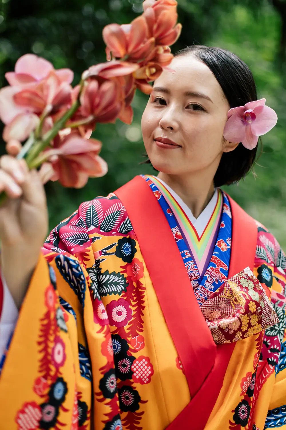 蘭の花を手に、こちらを見る琉装の女性