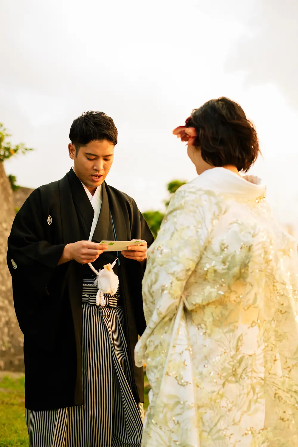 夕陽の中で、手紙を読む紋付姿の男性と白無垢の女性