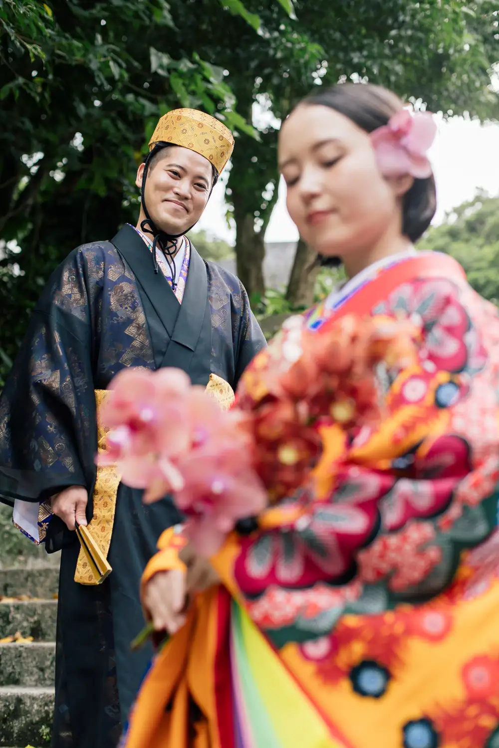 琉装のふたりが寄り添い、花束を見つめている